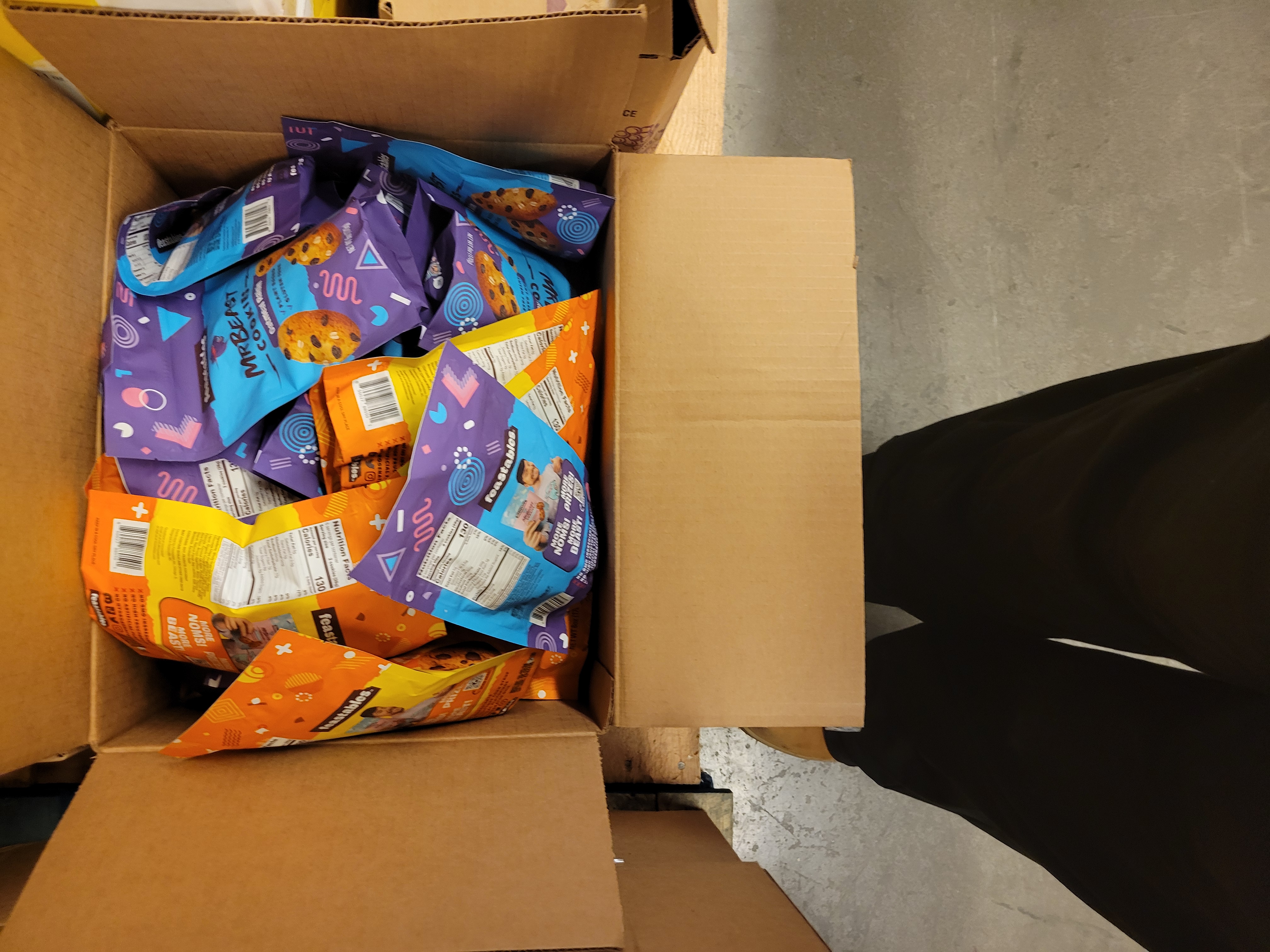 Cardboard box full of bags of different cookies.